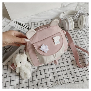 Close-up of pink and beige round crossbody bag with cute 3D ears and plush bear charm