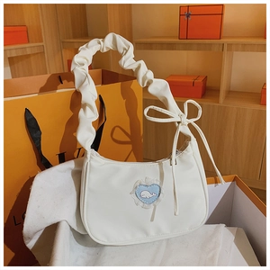 Detail der weißen hobo-tasche mit blauem herz-patch und gerafftem schleifenzug-griff
