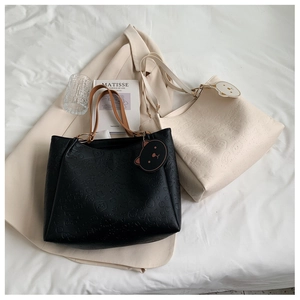 Detail of embossed leather tote bags in black and white with cute bear charms