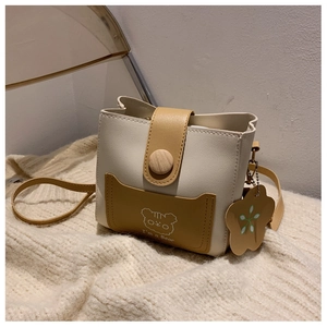 Detail of a white and yellow bucket bag featuring a cute bear print and flower charm