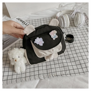 Detail of cute canvas crossbody bag with bunny ears, bear patch and plush charm accessory