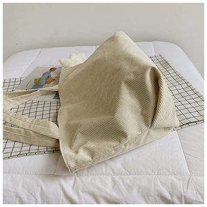 Detailed texture of beige corduroy tote bag showing vertical ribs on white bedding