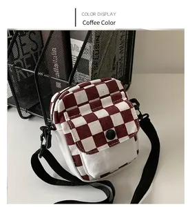 Detail einer braun-weiß karierten Canvas-Minibag mit verstellbarem schwarzem Gurt