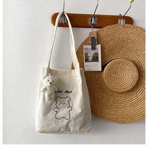 Dettaglio della borsa tote in velluto beige con ricamo a orsetto e ciondolo in peluche