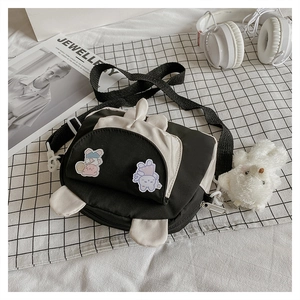 Detail of canvas crossbody bag with cartoon bunny ears and a plush bear keychain