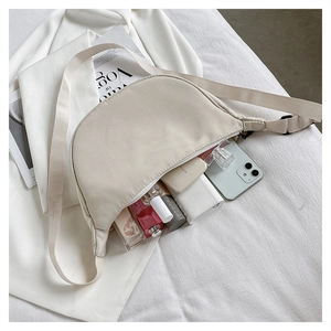 Detail of cream-colored nylon crescent bag showing interior capacity and wide shoulder strap