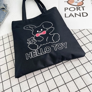 Black canvas tote bag with white cartoon bunny and Hello Toy text on checkered background