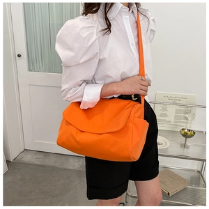 Model wearing a large orange nylon crossbody bag, showing its high capacity and casual style