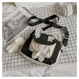 Detail of cute panda-themed canvas crossbody bag with cartoon patches and adjustable strap