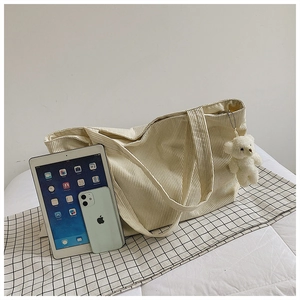 Detailed macro view of beige corduroy tote bag texture with cute white bear plush pendant