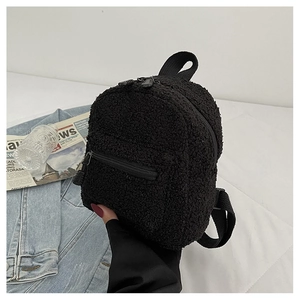 Detail of black sherpa fleece mini backpack showing fluffy texture and zipper pockets