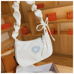 Detail der weißen Nylon-Schultertasche mit Faltenriemen und Herz-Wal-Aufnäher aus Spitze