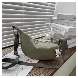 Olive green nylon crescent bag with adjustable strap and a cute cow pendant accessory