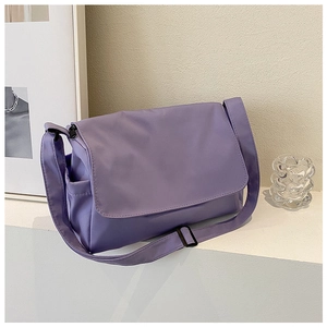 Detail view of purple nylon crossbody bag with flap closure and adjustable strap