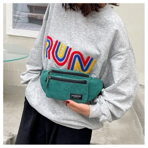 Detailed view of dark green corduroy chest bag featuring vertical texture and dual zippers