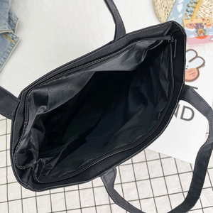 Large black canvas tote bag with internal zipper pocket and spacious interior structure