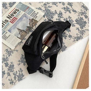 Detail of black corduroy chest bag showing fabric texture and fashion instinct label