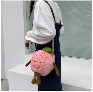 Detail of pink plush peach crossbody bag with smile embroidery and metal chain strap