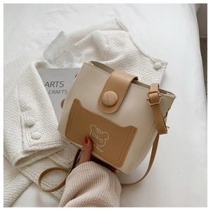 Detail of a two-tone bucket bag featuring a cute bear print and wooden button closure