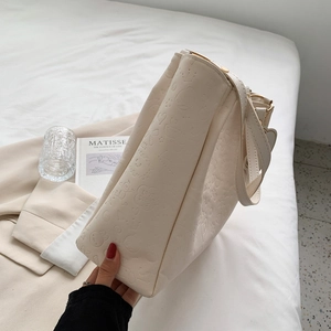 Minimalist beige embossed tote bag with cartoon patterns on soft white bedding