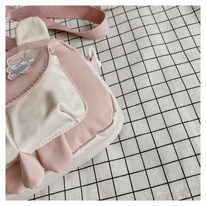 Detail of pink cartoon crossbody bag with shoulder strap buckle and decorative badge