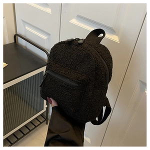 Detail showing the fluffy black fleece texture and front pocket of this mini backpack