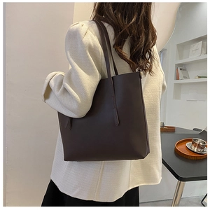 Deep brown large tote bag with matte leather texture shown on shoulder for daily commute