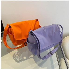 Close-up of orange and purple nylon messenger bags with adjustable straps and side pockets