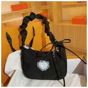 Detail einer schwarzen Stofftasche mit Rüschenriemen, Schleife und Wal-Herz-Patch-Design