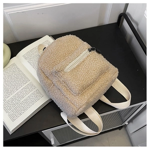 Detailed texture of beige faux shearling mini backpack next to a vintage book