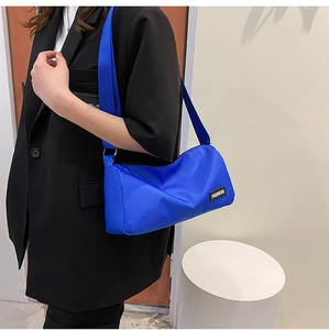 Détail du sac bandoulière bleu Klein avec bandoulière large et étiquette tissée