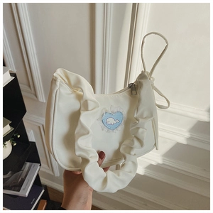 Detail der weißen Plissee-Tasche mit Wal-Herz-Patch und Spitzenverzierungen