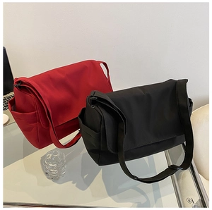 Close-up of red and black nylon crossbody bags with durable fabric straps and flap closure