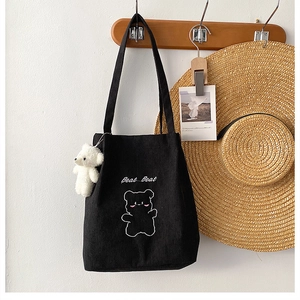 Dettaglio borsa tote in velluto a coste nero con ricamo orsetto e ciondolo di peluche