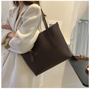 Detail of a large dark brown faux leather tote bag with adjustable strap for office use