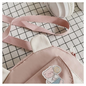 Detailed view of pink cartoon pig embroidery on a two-tone nylon crossbody bag