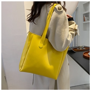 Detailed view of the bright yellow tote bag worn with a chic beige trench coat