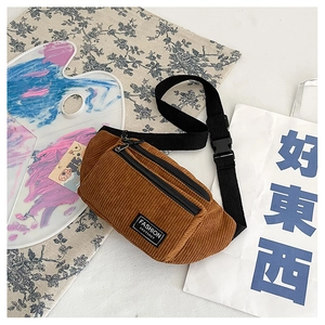 Detail of caramel corduroy chest bag featuring a black 'FASHION INSTINCT' woven label