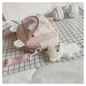 Detail of pink cartoon rabbit crossbody bag with bear pendant on checkered cloth