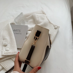 Minimalist cream and brown bucket crossbody bag with gold hardware and adjustable strap