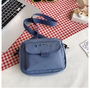 Detailed view of blue nylon crossbody bag with DANCE logo and adjustable strap
