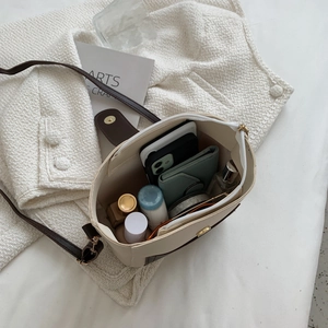 Contrast color bucket bag shown with interior storage for phone and cosmetics