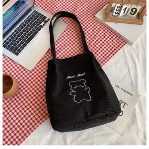 Dettaglio della borsa tote in velluto a coste nero con ricamo a orso e tracolle