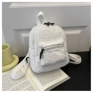 Detail of white sherpa mini backpack with front pocket and black zippers on an open book
