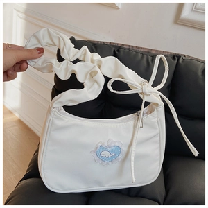 Detail der weißen Plissee-Schultertasche mit blauem Herz-Patch und Wal-Stickerei