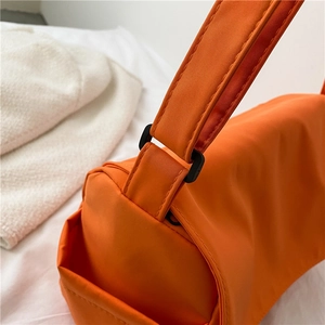 Orange nylon crossbody bag with black buckle detail and durable waterproof fabric texture