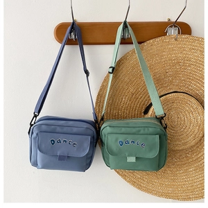 Detail view of stylish nylon messenger bags in blue and green with Dance lettering