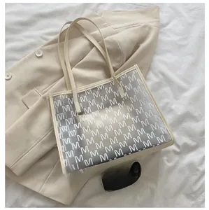 Detail of clear tote bag with M-pattern print and leather trim showing large interior space