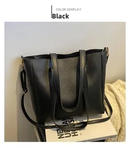 Close-up of black pebble leather tote bag featuring gold-tone hardware and crossbody strap