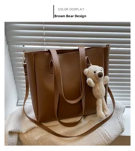 Brown leather tote bag detail with cute plush bear charm and long shoulder strap